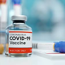 vial of COVID-19 vaccine on a table next to a syringe