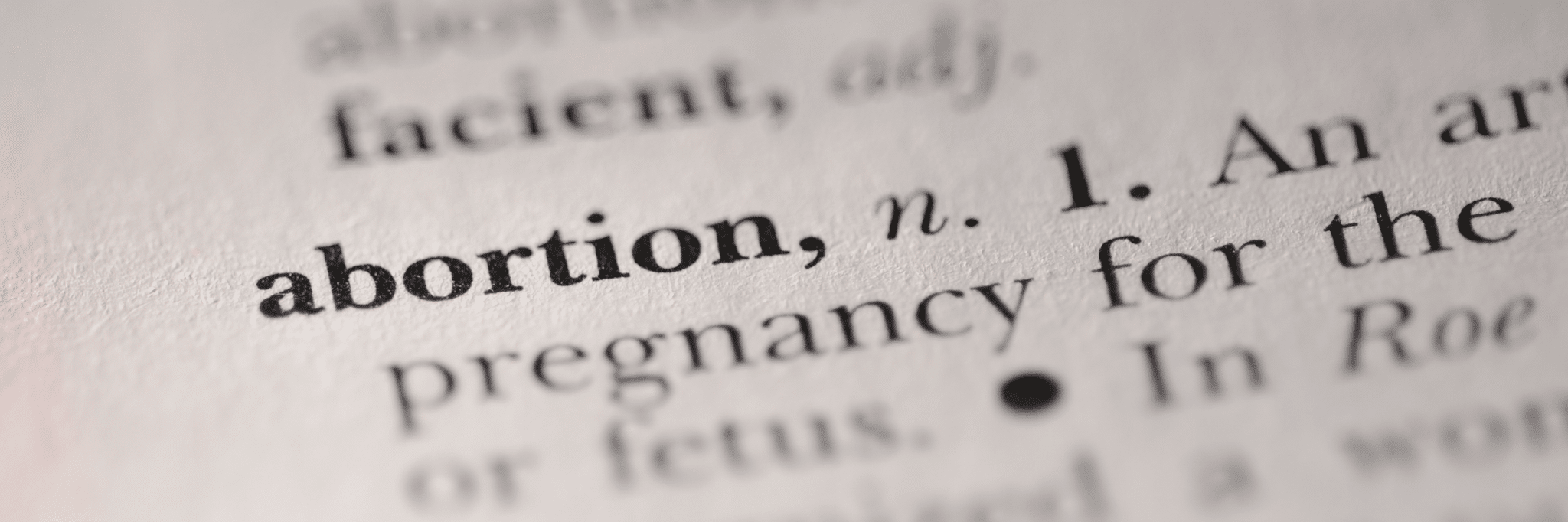 a page listing definitions; "abortion" is in focus and its definition is faded near the borders of the image.